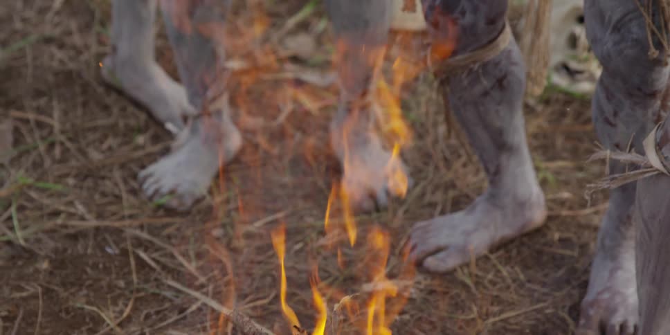 A man stands over a fire