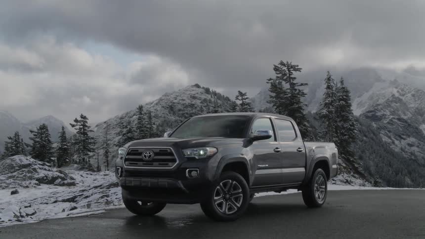A pickup truck parked on the road with trees and mountains in the background