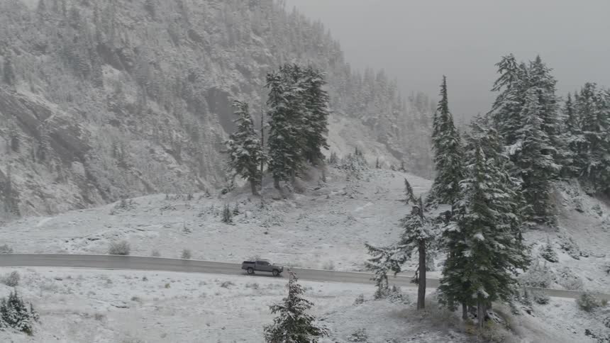 A truck drives through snowy mountains