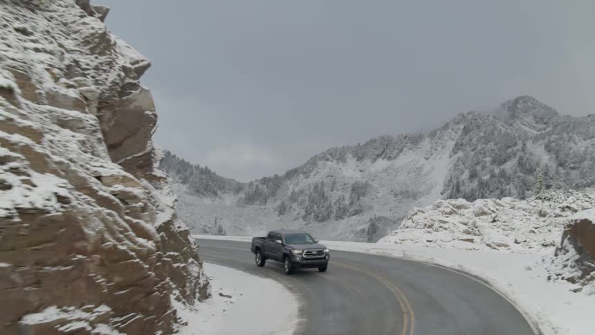 Skyline view of a truck driving through the snow covered mountains
