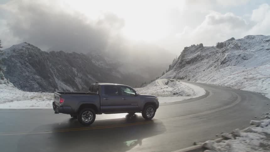 A truck driving down an icy road in a mountain