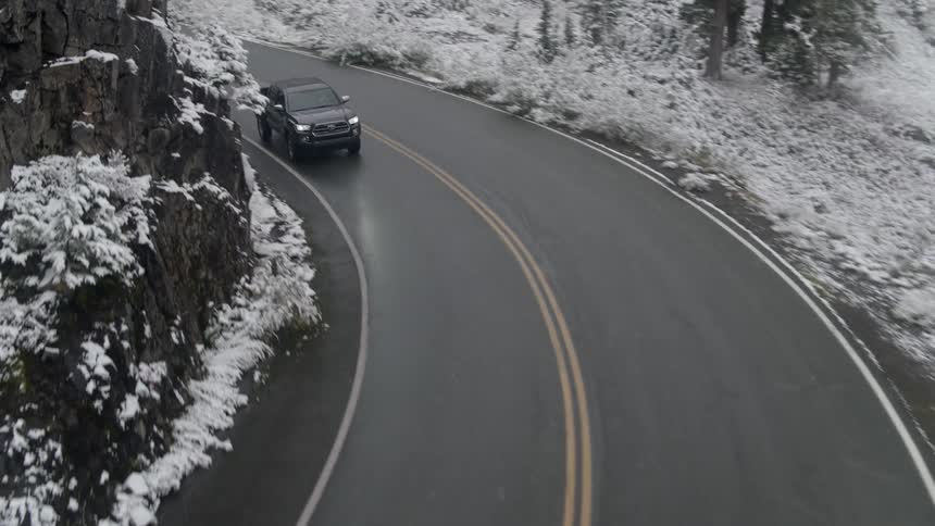 Truck drives along road through snow and frost covered forest