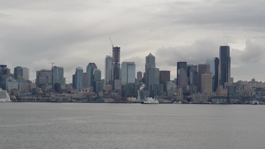 A ship is sailing past the city in the distance