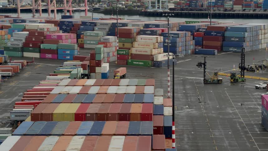Stacks of shipping containers at a shipyard during the day