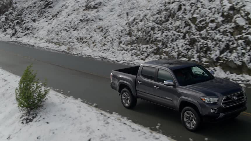 A black truck traveling down the road on a snowy mountain