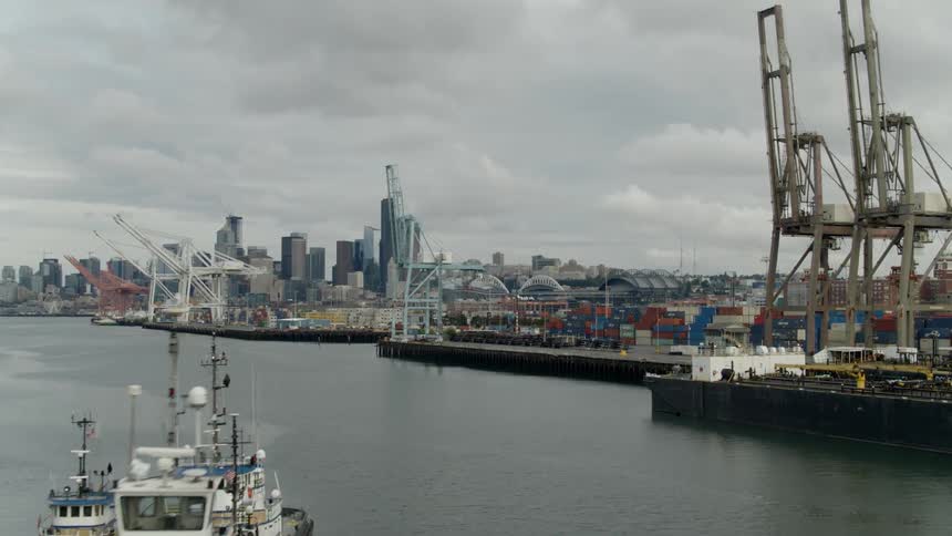 A large shipping container port near a river by a large city skyline