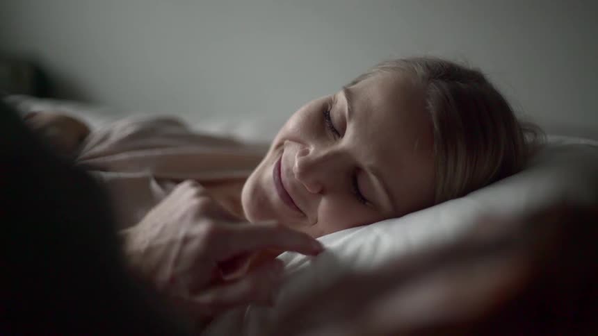 A man touches a womans nose in bed