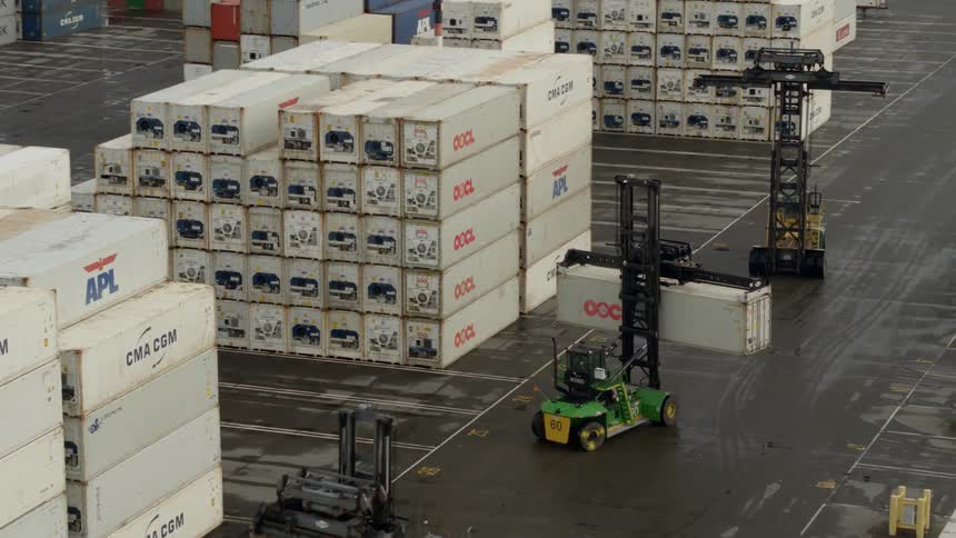 Forklifts lift and move shipping containers in a shipyard