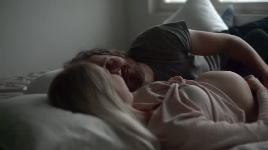 A man and pregnant woman lay in bed together