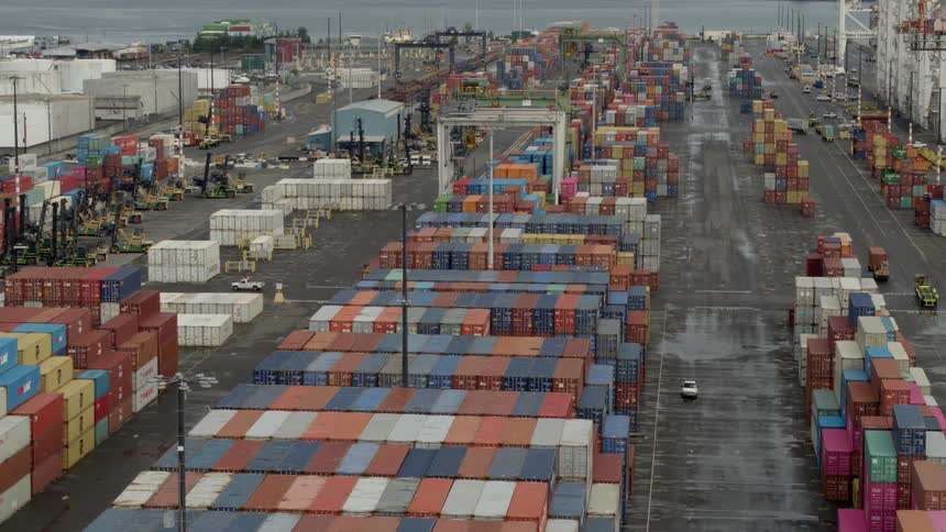Vehicle drives between stacks of shipping containers at the docks