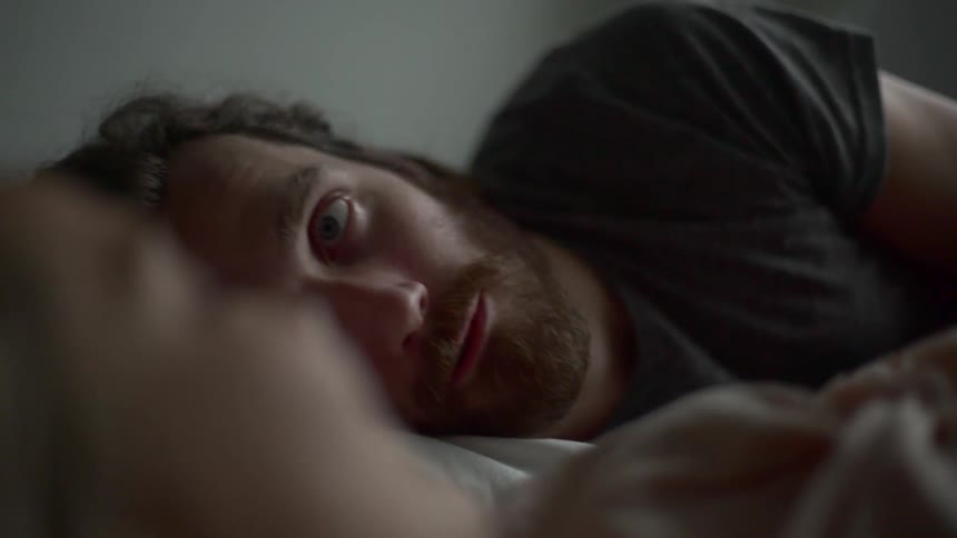 A man and a woman laying in bed looking at each other