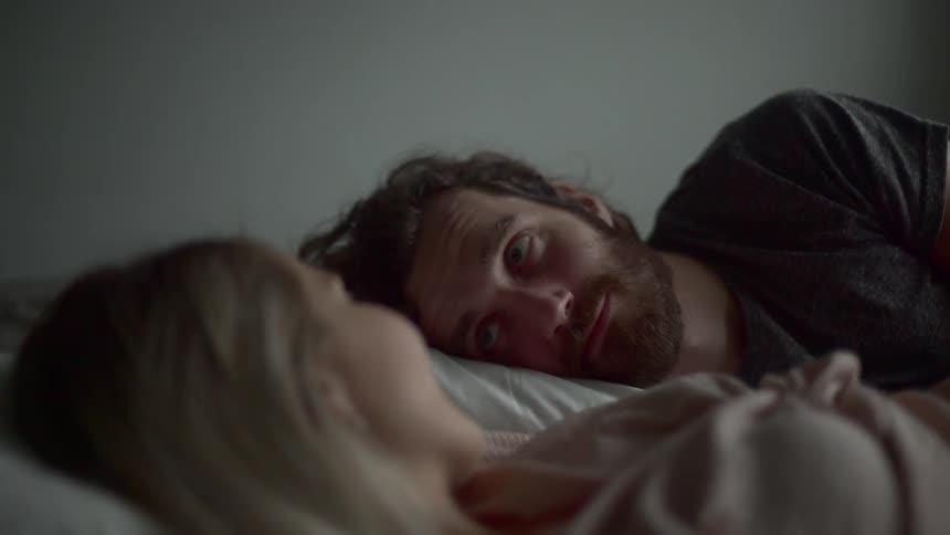 A man and woman laying in a bed next to each other