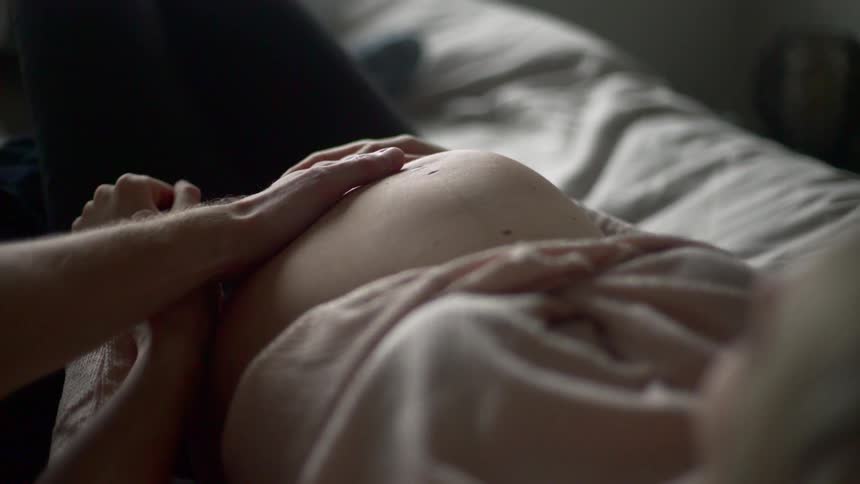 A man caresses his pregnant partners navel