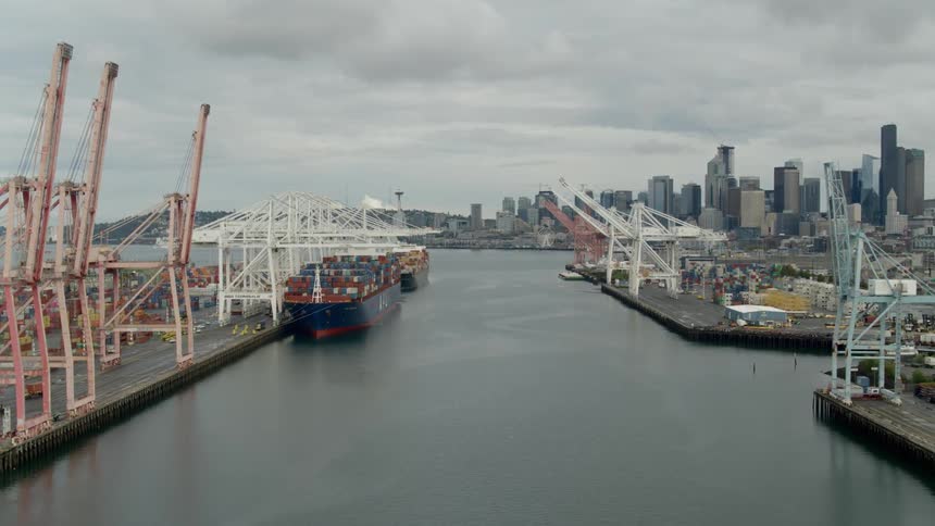 Two ships filled with cargo containers sit docked in a city port