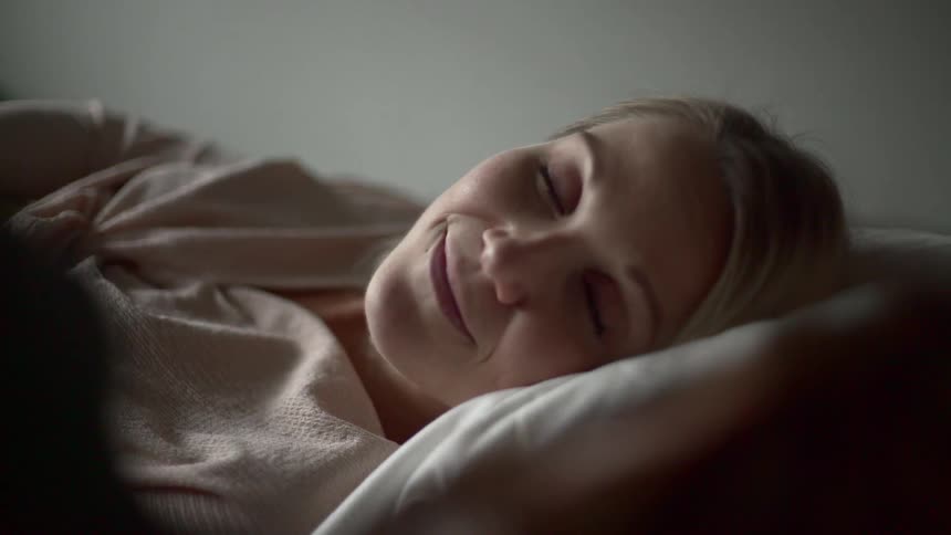 A woman lying in bed smiles and looks over at the person lying next to her