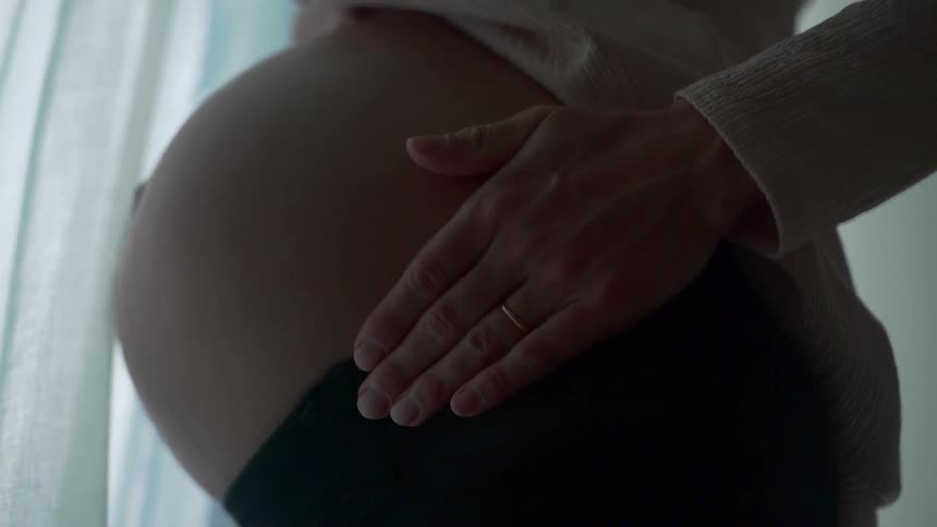 A woman is rubbing her pregnant belly
