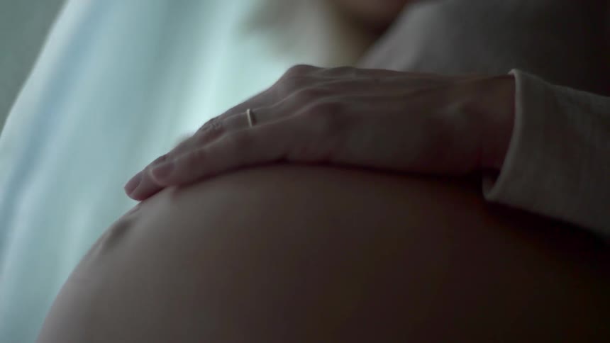 Woman rubs her pregnant stomach