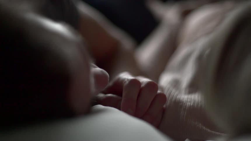 A man tickles the nose of the woman laying next to him