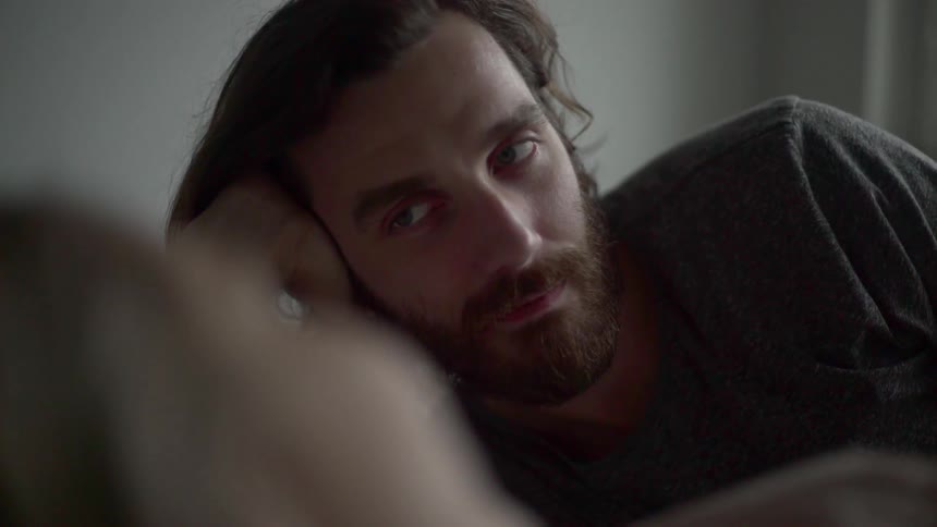 A bearded man rests his head and stares longingly into the person next to him
