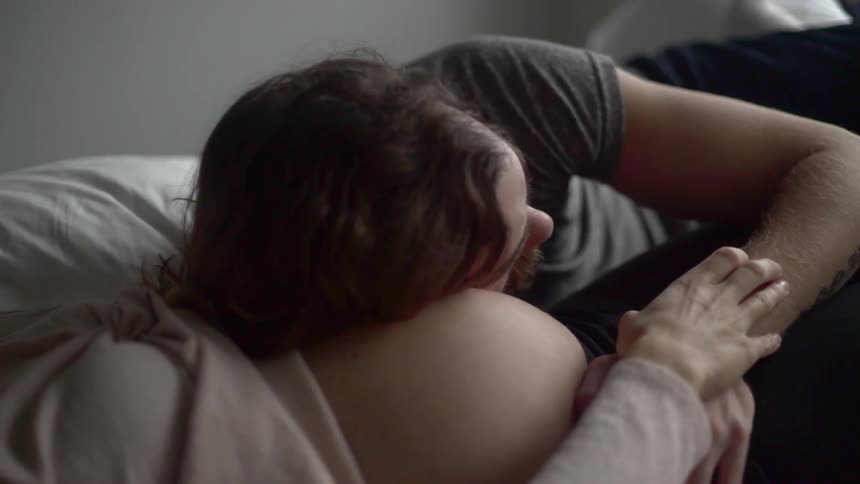 A man laying on a womans stomach while she is pregnant