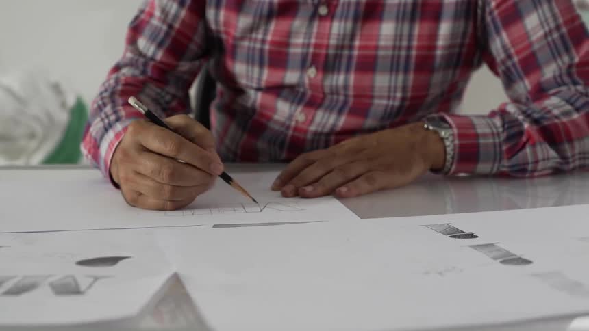 The man is drawing on a large paper