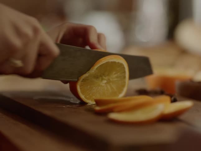 A white person uses a knife to cut an orange