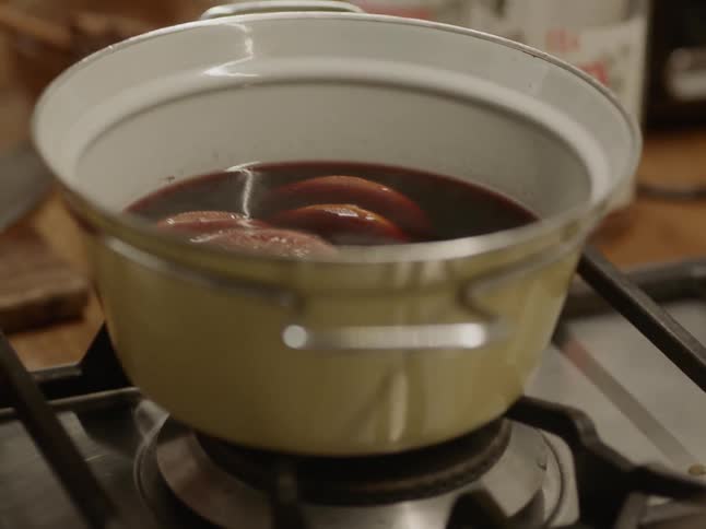 A cook removing the lid from a yellow enamel pot on a stove