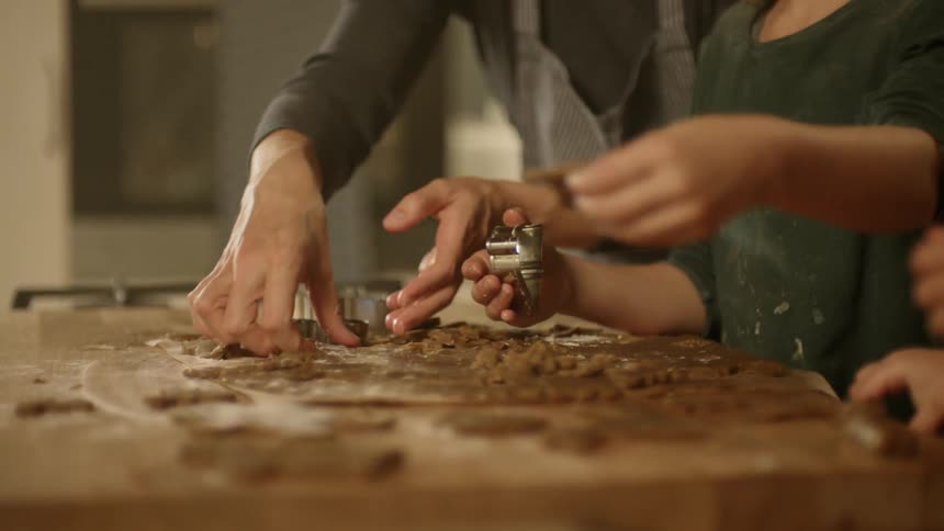 A group of people slicing dough with cookie cutters