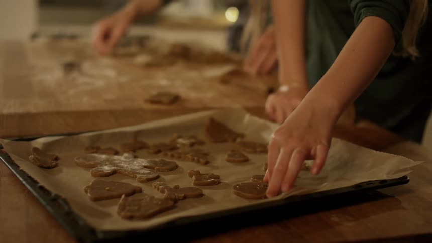 A child places cookies on a baking sheet