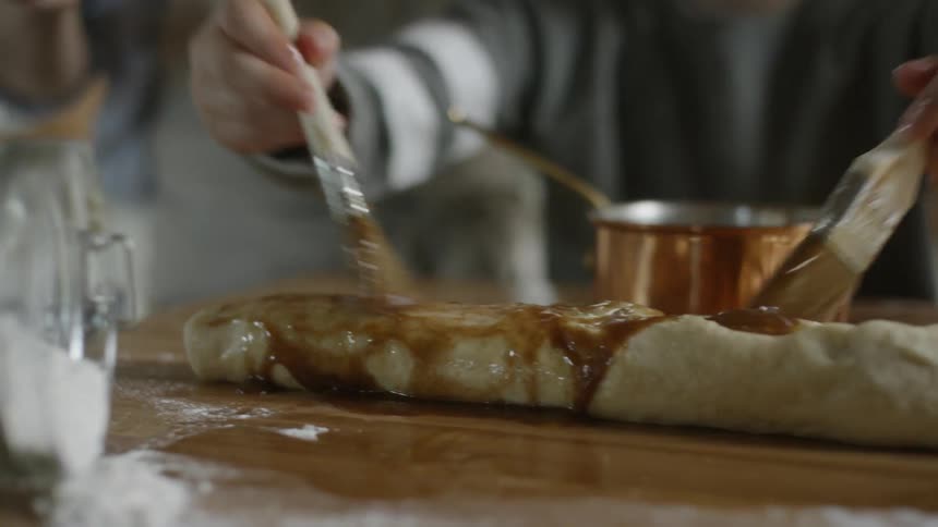 A person is brushing gravy over food