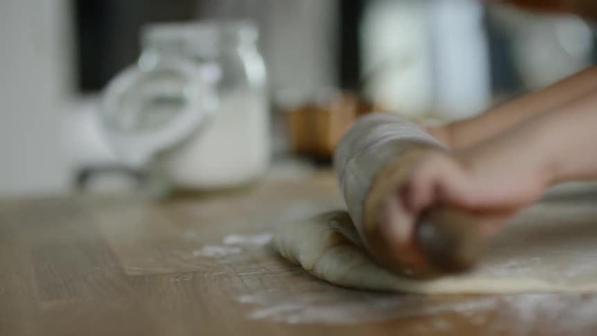 A child rolling dough on a large counter