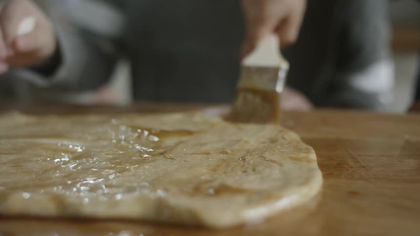Two white kids paint a piece of dough with brushes