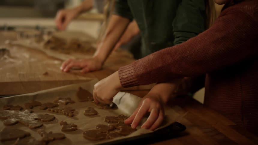 Children put shaped cookie dough onto a baking sheet in a kitchen