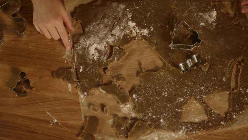 Two people making shapes in dough using cookie cutters