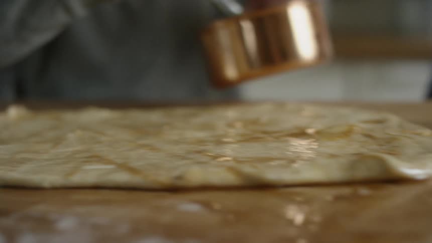 Two people glazing dough with pastry brushes
