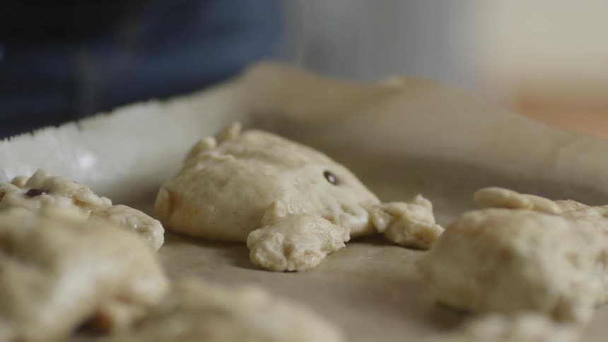 Chocolate chips being placed on puffy pastries