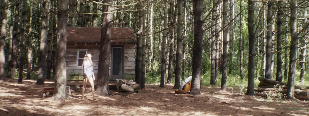 A woman looks up at the trees as she walks by a cabin