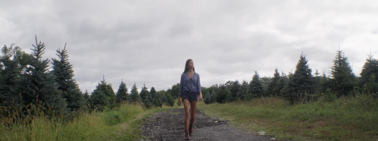 Woman walking a dirt trail through a meadow