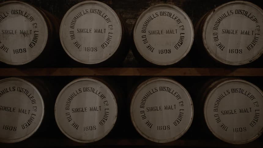 Camera trucking left showing a wall of whiskey barrels