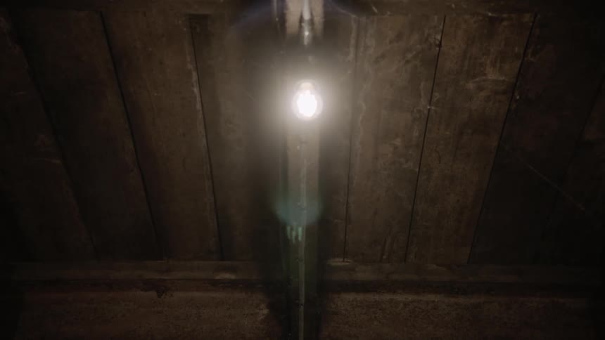 The underside of dusty and cobweb filled floorboards with a single light bulb
