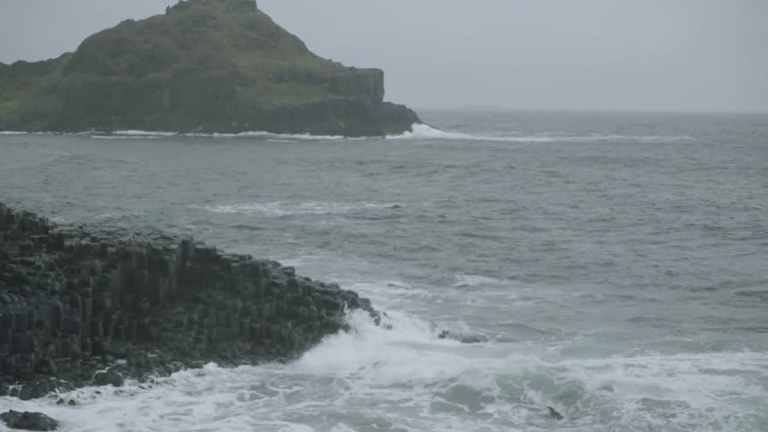 Surf splashing against shore on hazy day