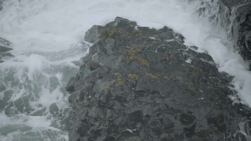 Large waves crashing over moss covered rocks