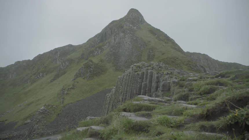 A bird flying over a steep grass covered mountain and hillside
