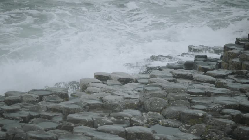 The waves crash and move over the stones