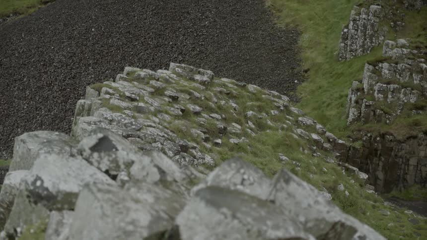 The rocks are leading up to a mountain with grass