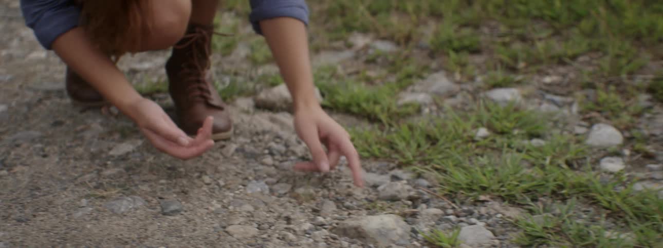 A woman crouching and holding a bug in her hands