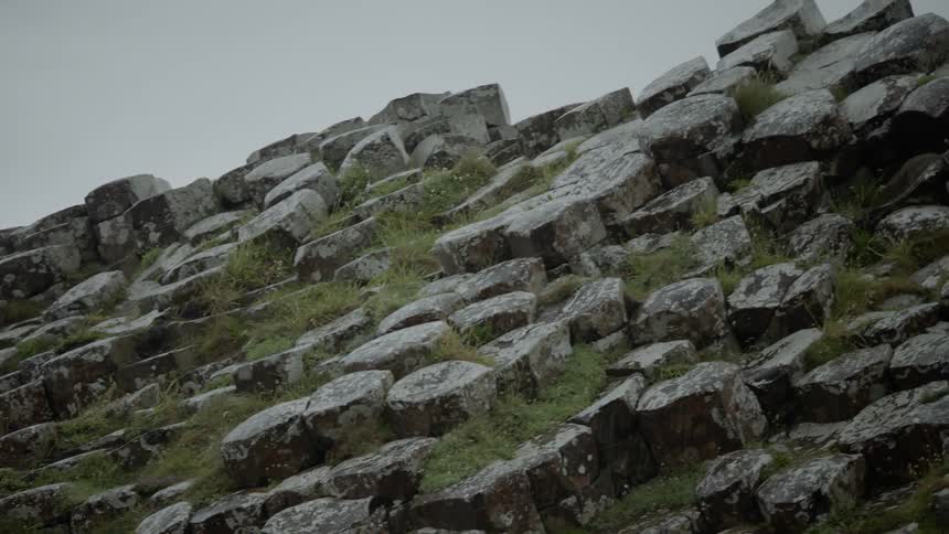 Rocks and grass cover a hillside on a cloudy day