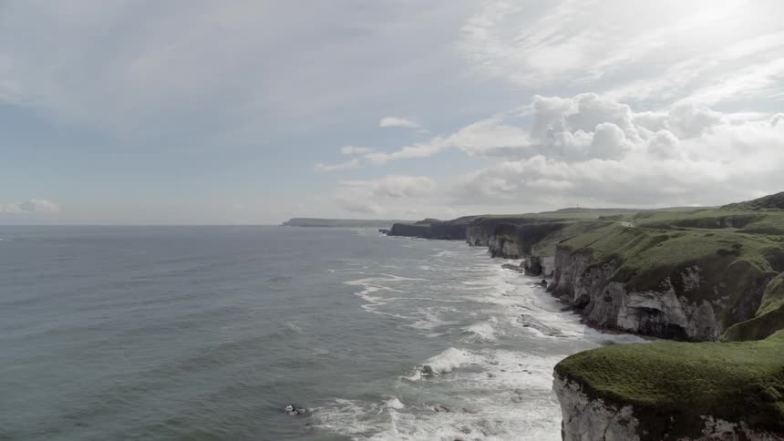 A steep rocky grass covered mountain along the sea
