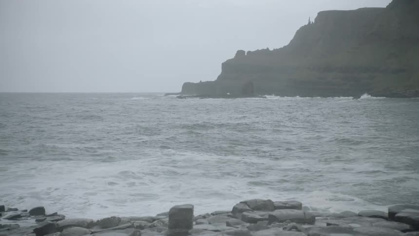 A bay surrounded by cliffs and rocky shore on a foggy day