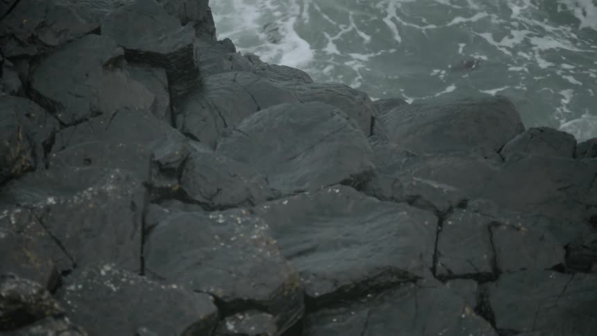 Ocean waves splash and foam against a rocky shore